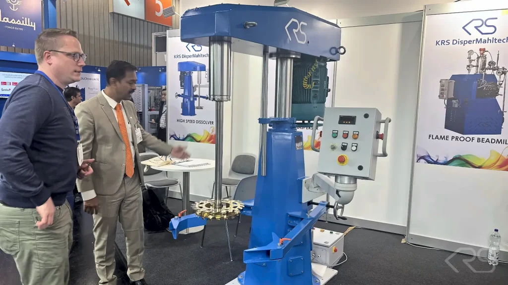Visitors at the KRS stand at ECS 2025 next to a High Speed Disperser with control panel